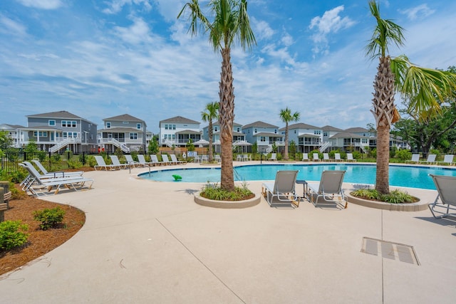 community pool with a patio, fence, and a residential view