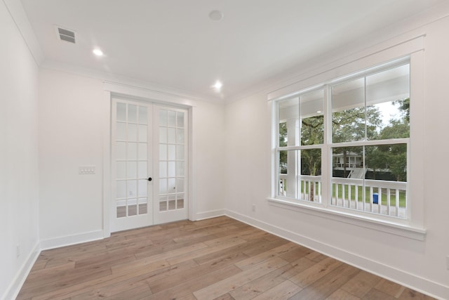 empty room with light wood-style floors, crown molding, french doors, and visible vents