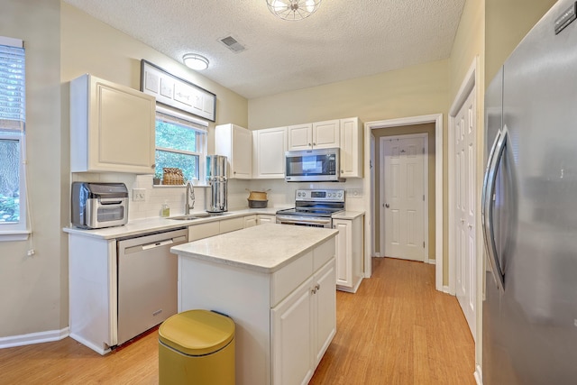 1972 Gray Battery Ct, Mount Pleasant, SC 29464 - kitchen featuring stainless steel appliances, light wood-type flooring, light countertops, a textured ceiling, and white cabinetry