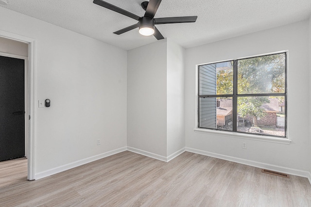 empty room with ceiling fan, light hardwood / wood-style flooring, and a textured ceiling