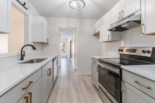 kitchen with sink, appliances with stainless steel finishes, a textured ceiling, white cabinets, and light wood-type flooring