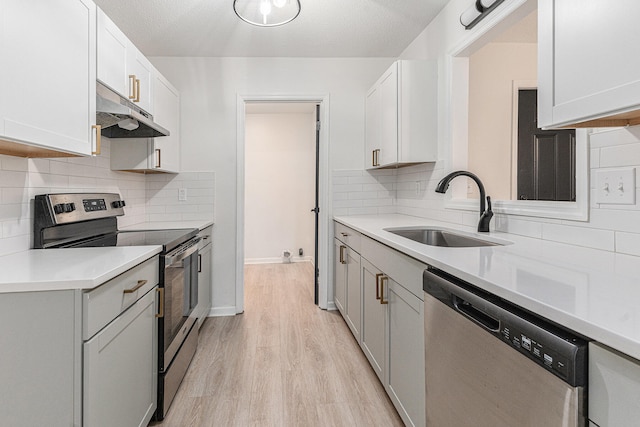 kitchen featuring white cabinetry, sink, appliances with stainless steel finishes, and light hardwood / wood-style flooring