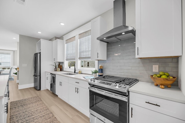 101 Hanover St, Charleston, SC 29403 - kitchen with wall chimney range hood, appliances with stainless steel finishes, decorative backsplash, light wood finished floors, and light countertops