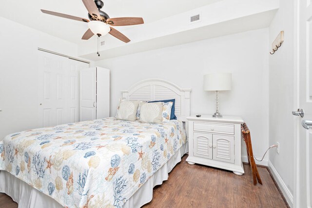 bedroom with ceiling fan, dark wood-type flooring, and a closet