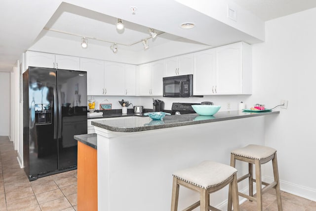 kitchen with black appliances, white cabinets, kitchen peninsula, and a breakfast bar area