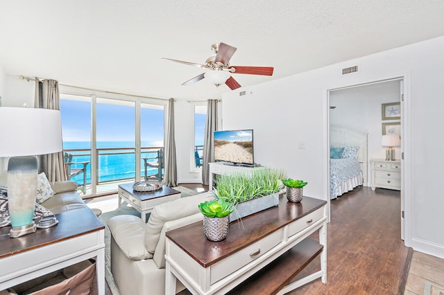 living room featuring ceiling fan, a wall of windows, and wood-type flooring