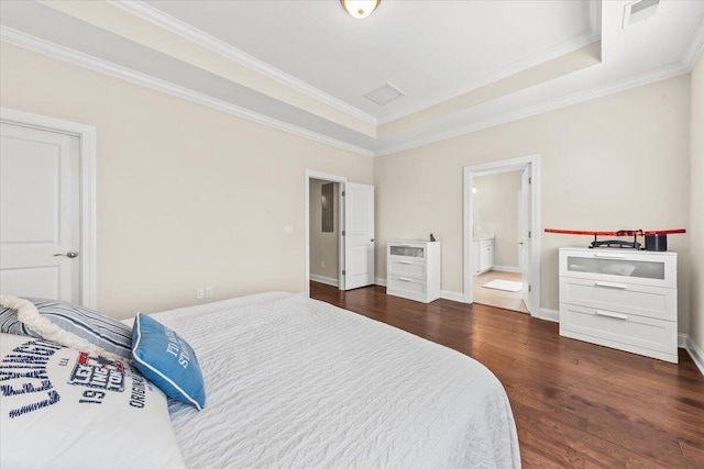 bedroom featuring ornamental molding, dark wood-style flooring, a tray ceiling, baseboards, and connected bathroom