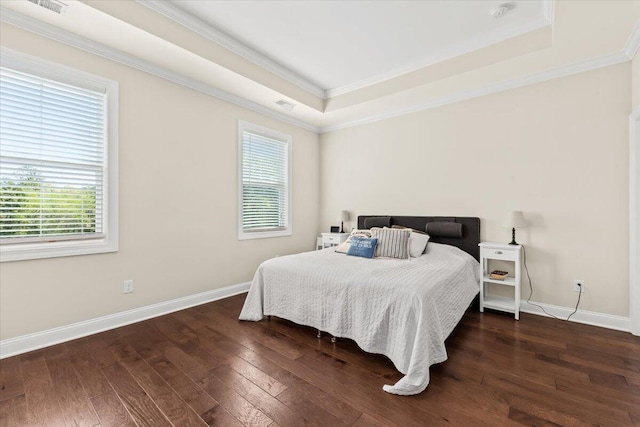 bedroom featuring multiple windows, dark wood-style flooring, a tray ceiling, and ornamental molding