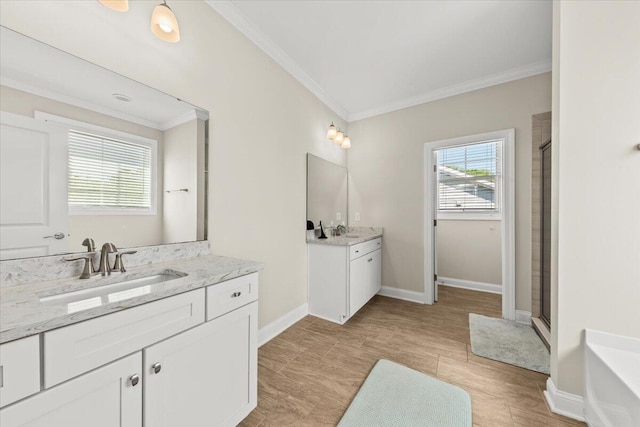bathroom featuring ornamental molding, a shower stall, two vanities, baseboards, and a tub to relax in