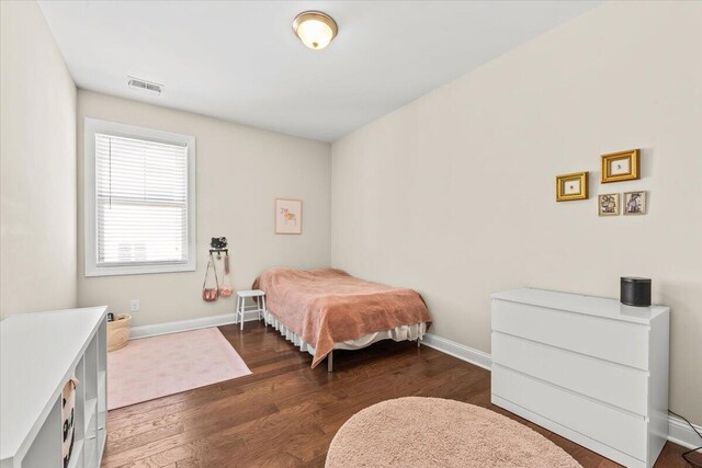 bedroom with dark wood-type flooring and baseboards