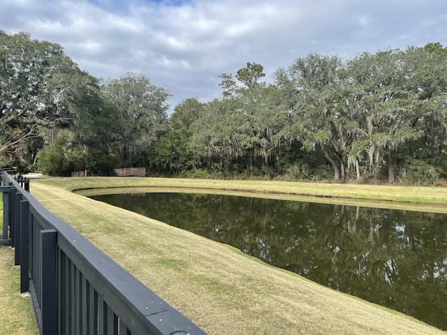 view of green lawn featuring a water view and view of scattered trees