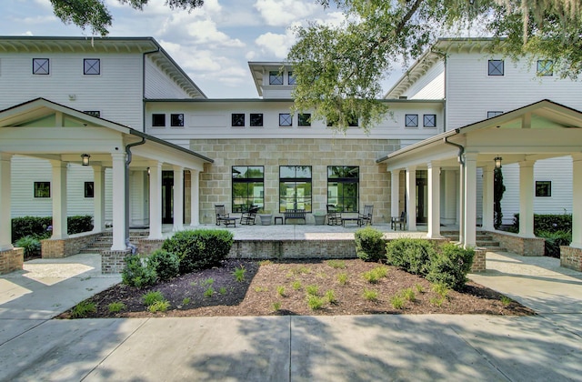 rear view of house with a porch and stone siding