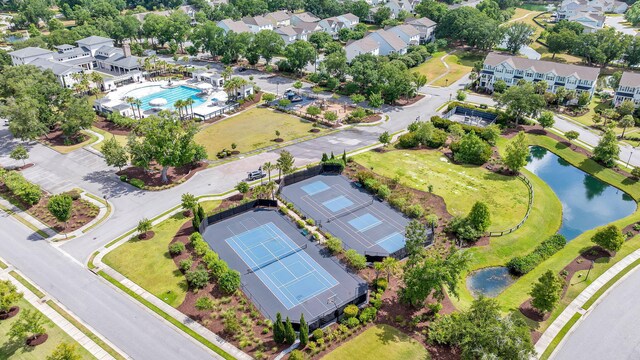 aerial perspective of suburban area featuring a pool and a large body of water