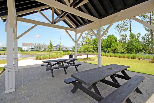 view of home's community with outdoor dining area, a lawn, a patio area, a water view, and a residential view