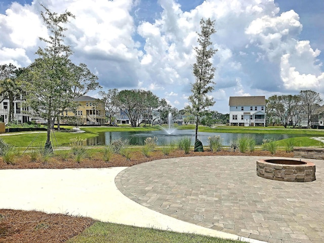 surrounding community with a water view and an outdoor fire pit