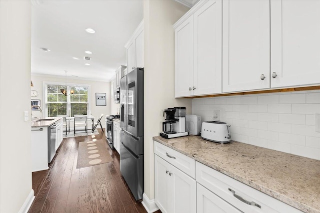 kitchen with stainless steel appliances, dark wood-style floors, a sink, white cabinetry, and backsplash