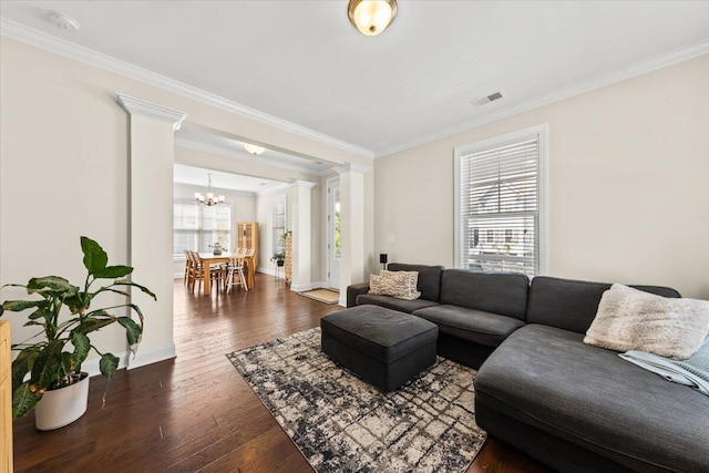 living area with a chandelier, hardwood / wood-style floors, decorative columns, ornamental molding, and baseboards