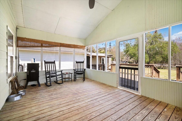 unfurnished sunroom with a deck, lofted ceiling, wood finished floors, and ceiling fan