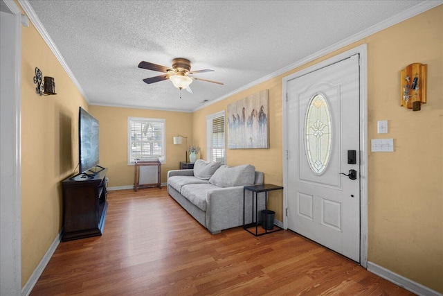 entrance foyer with wood finished floors, baseboards, ornamental molding, ceiling fan, and a textured ceiling