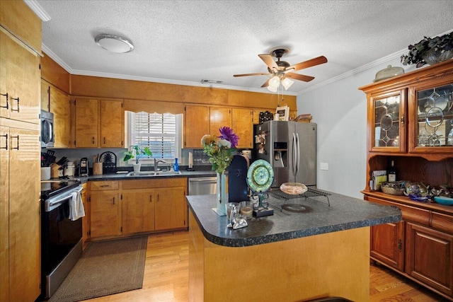 kitchen featuring dark countertops, appliances with stainless steel finishes, light wood-style floors, and a sink