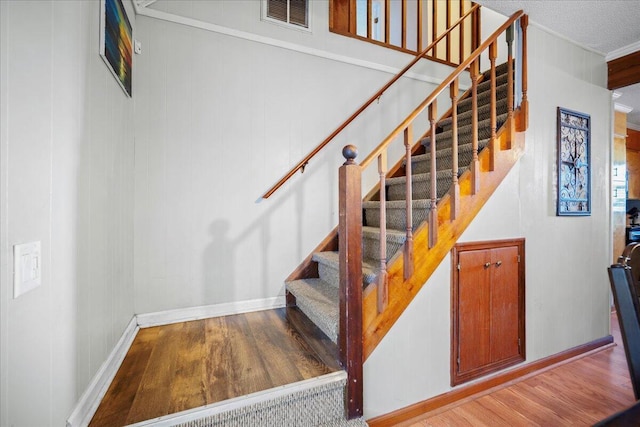 stairway featuring visible vents, baseboards, and wood finished floors