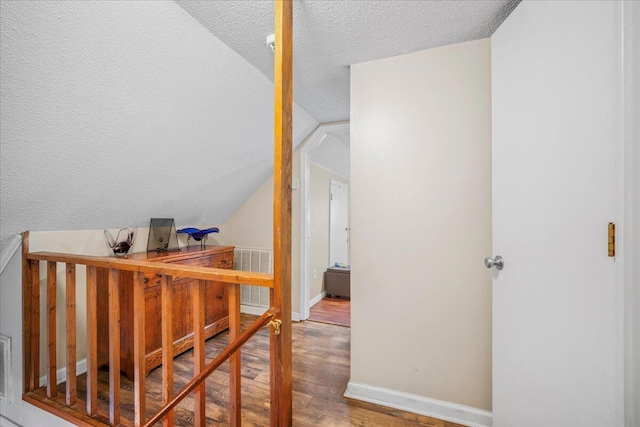 bonus room with visible vents, a textured ceiling, wood finished floors, baseboards, and vaulted ceiling