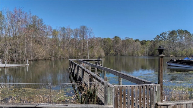 view of dock with a wooded view and a water view