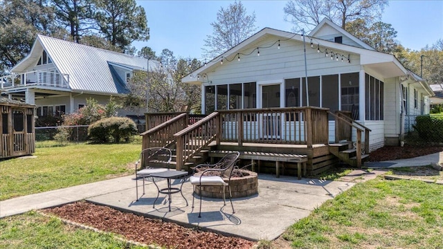 rear view of house featuring a deck, a lawn, fence, and a sunroom