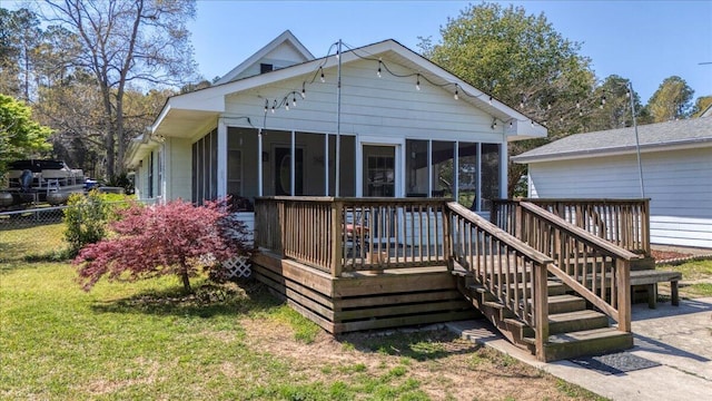 rear view of house with a deck, a yard, fence, and a sunroom