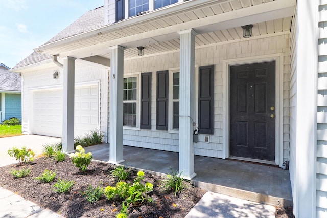 view of exterior entry with covered porch, roof with shingles, and an attached garage