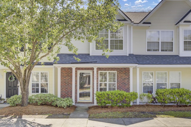 multi unit property featuring roof with shingles and brick siding
