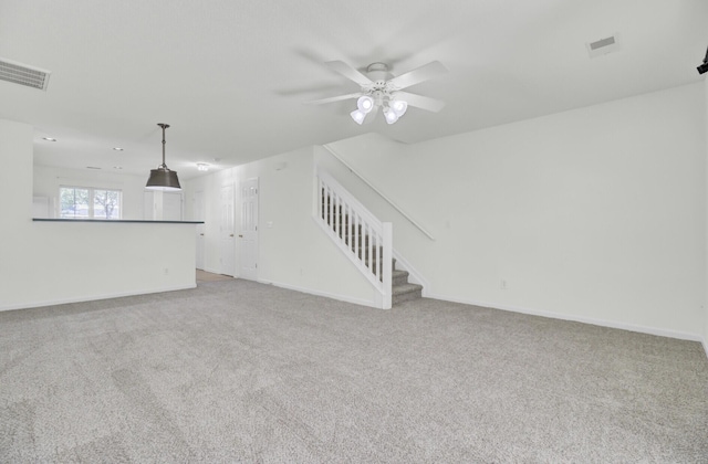 unfurnished living room with stairway, light carpet, and baseboards