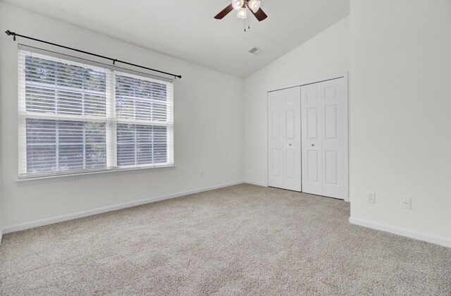 unfurnished bedroom with lofted ceiling, carpet floors, multiple windows, a closet, and baseboards