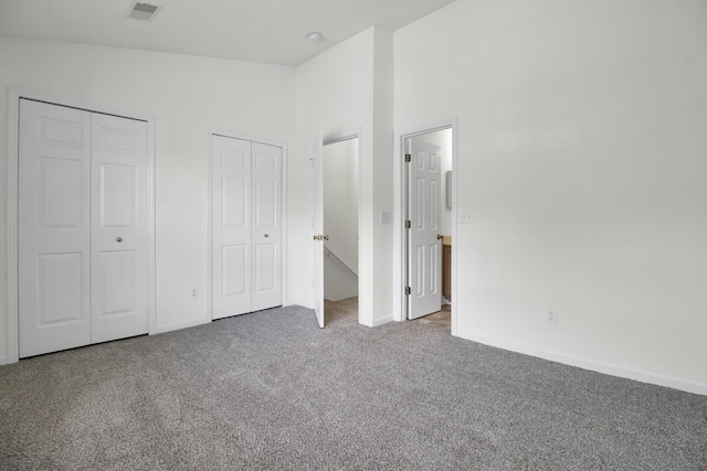 unfurnished bedroom featuring carpet flooring, multiple closets, and baseboards