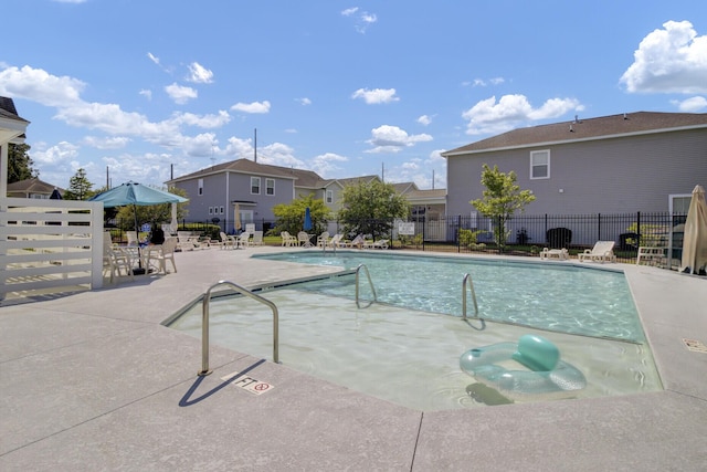 community pool with fence, a patio area, and a residential view