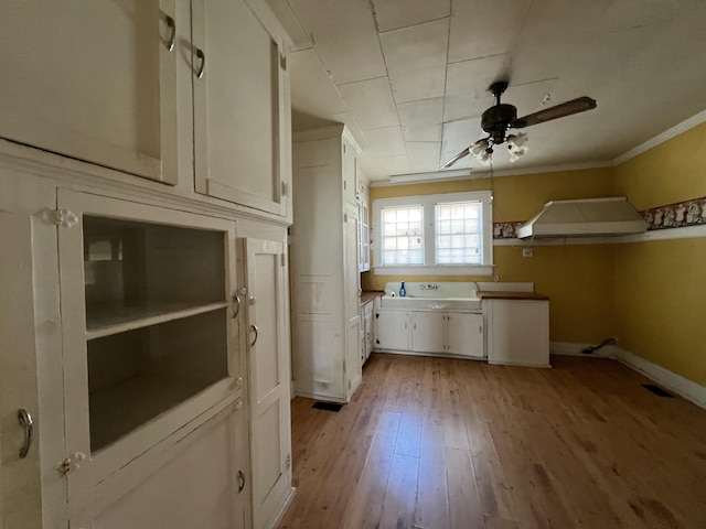 kitchen with light wood finished floors, crown molding, ceiling fan, extractor fan, and white cabinets