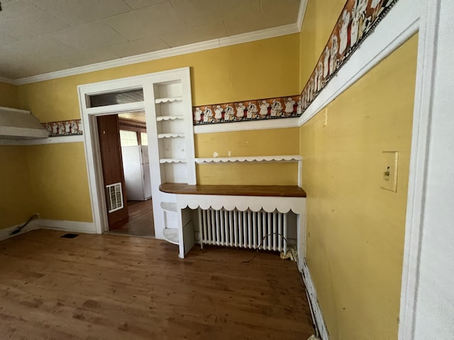 staircase featuring visible vents, wood finished floors, radiator heating unit, and ornamental molding