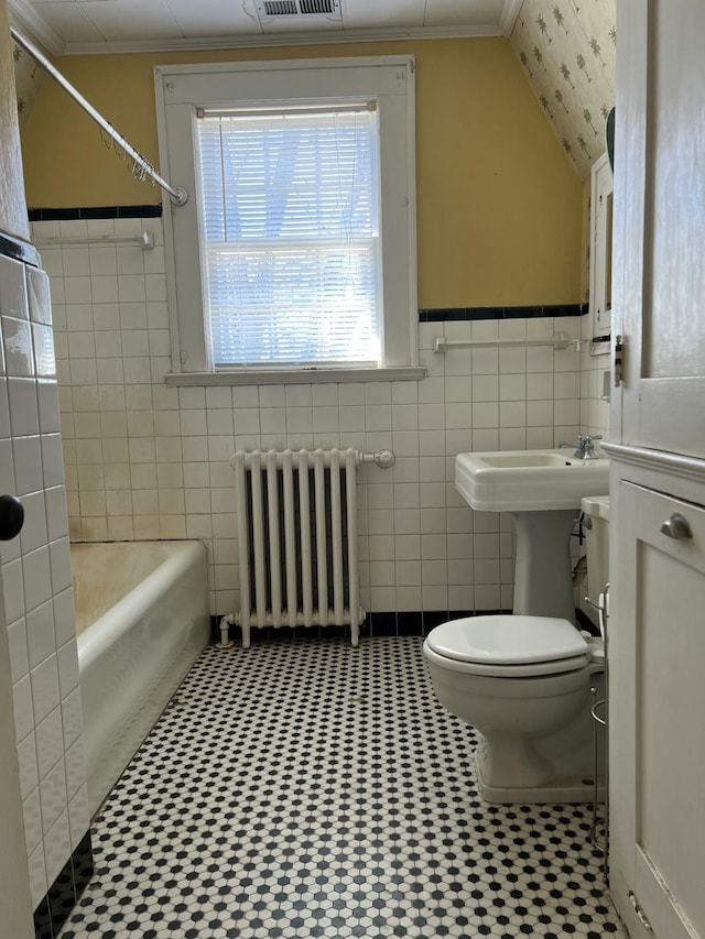 bathroom with lofted ceiling, radiator heating unit, ornamental molding, tile walls, and toilet