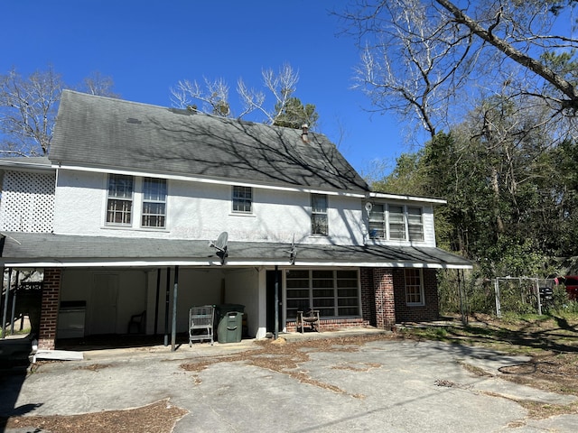 back of property with fence, brick siding, and driveway