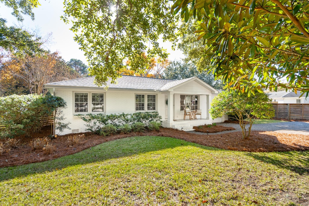 single story home featuring covered porch and a front lawn