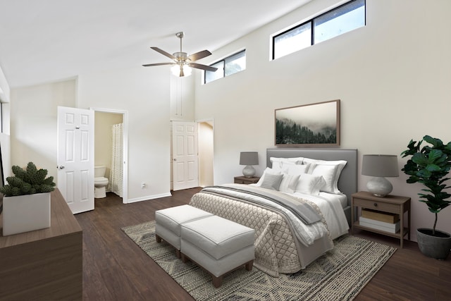 bedroom featuring dark wood-style flooring, a towering ceiling, ensuite bathroom, ceiling fan, and baseboards