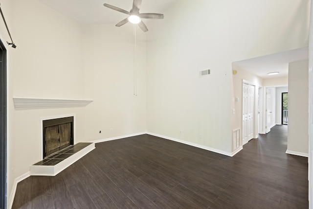 unfurnished living room featuring dark wood-style floors, a fireplace, visible vents, and a ceiling fan