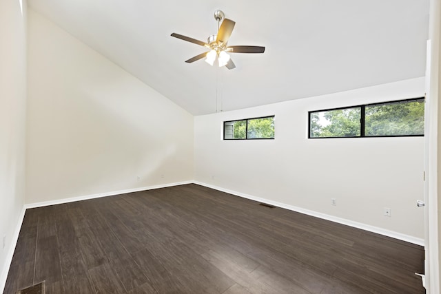 empty room featuring dark wood-style flooring, lofted ceiling, visible vents, a ceiling fan, and baseboards