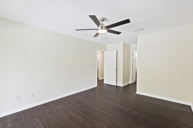 spare room with dark wood-style floors, visible vents, ceiling fan, and baseboards