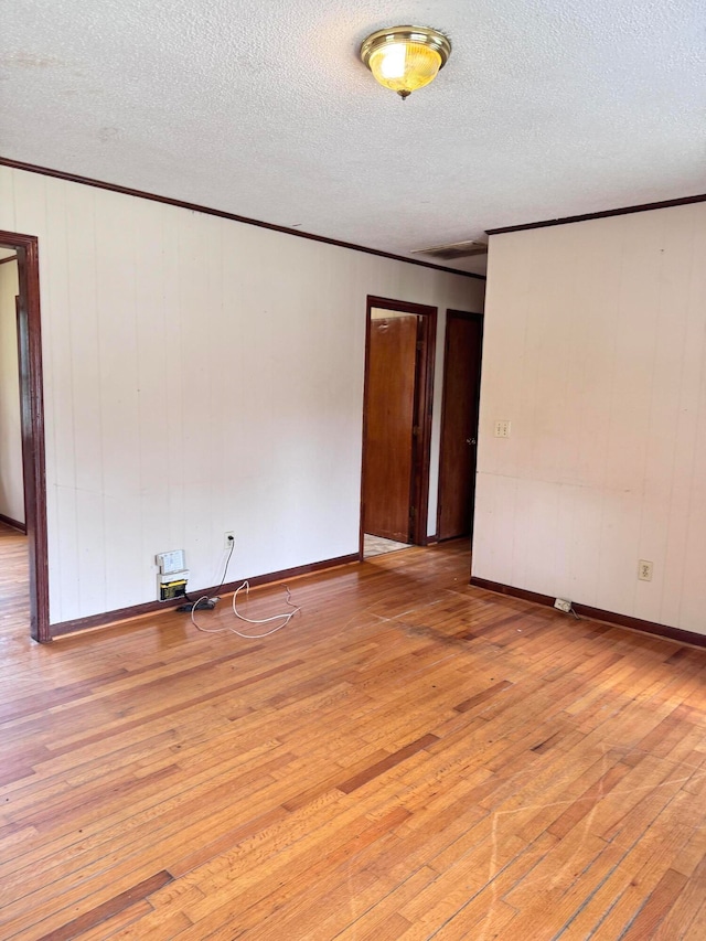 unfurnished room with a textured ceiling and light hardwood / wood-style floors