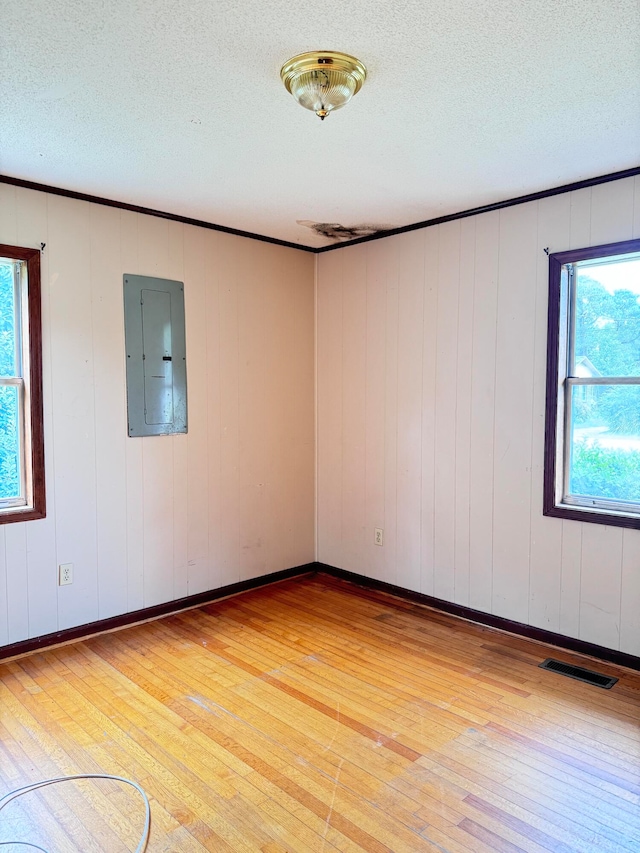 empty room with wood-type flooring, electric panel, and a textured ceiling