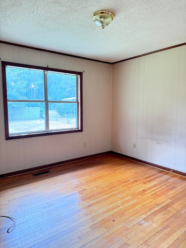 unfurnished room featuring a textured ceiling, plenty of natural light, and light hardwood / wood-style floors