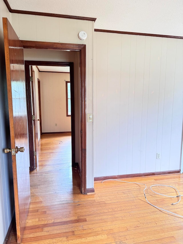 interior space with ornamental molding, wood walls, and light wood-type flooring