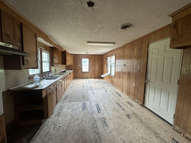 kitchen featuring wood walls, brown cabinets, and light countertops