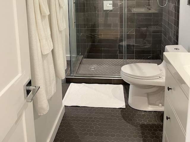 bathroom with toilet, tile floors, a shower with shower door, and vanity